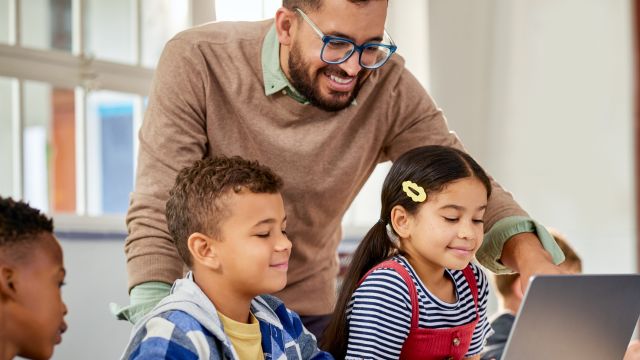 A family of four is gathered around a digital tablet, their faces lit up with excitement. They're all smiling and talking, and it looks like they're having a great time learning.